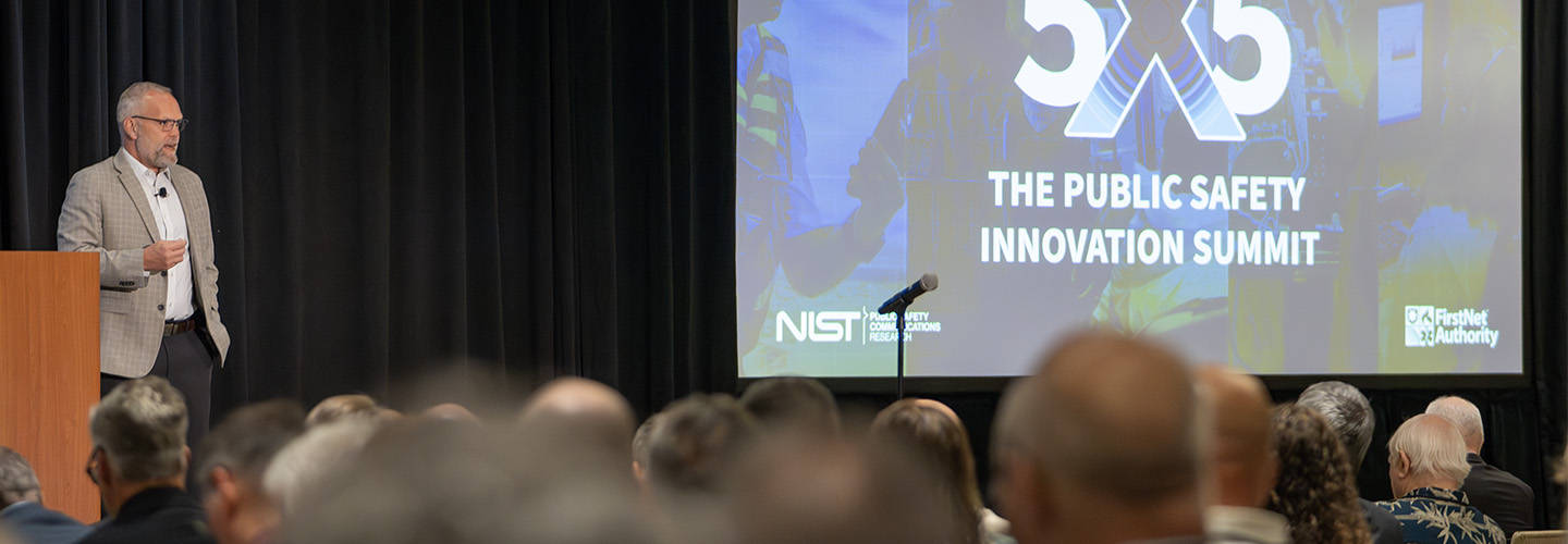 A speaker stands on the main stage at 5x5