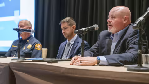 Three public safety leaders speak into microphones during a panel discussion at 5x5