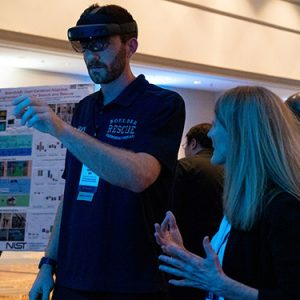 An attendee tries virtual reality glasses at 5x5 with the help of a tech demo host