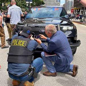 A police officer shows a 5x5 attendee a piece of technology during an outdoor tech demo